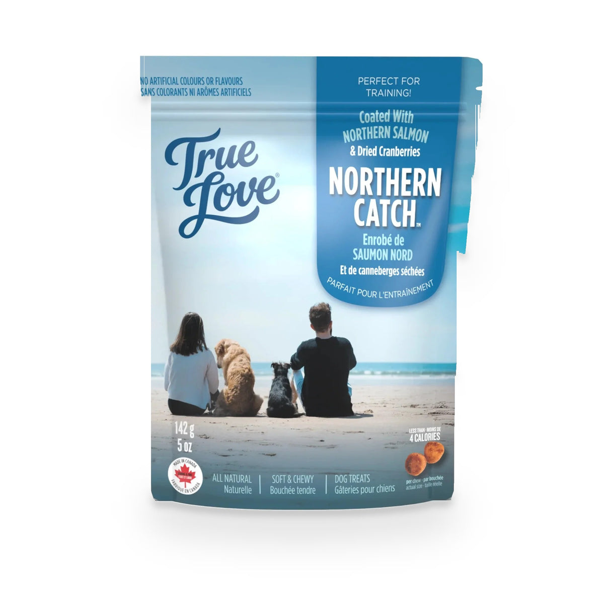 Bag of True Love dog treats with a family and their dogs on an ocean beach. Northern Catch flavour - northern salmon and dried cranberries.